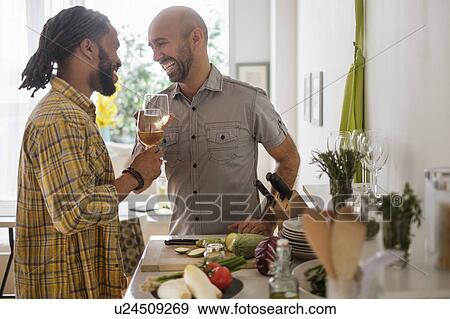 Smiley homosexual couple drinking wine in kitchen View Large Photo Image Stock Photo - Smiley homosexual couple drinking wine in kitchen. Fotosearch
