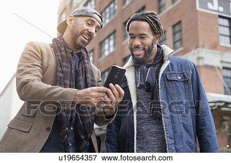 Smiley homosexual couple taking selfie with smart phone in street View Large Photo Image Stock Photo - Smiley homosexual couple taking selfie with smart phone in street. Fotosearch