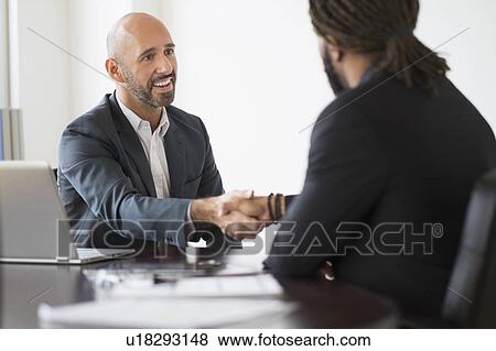 Smiling businessmen shaking hands in office View Large Photo Image Stock Photo - Smiling businessmen shaking hands in office. Fotosearch