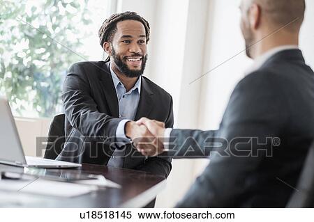 Smiling businessmen shaking hands in office View Large Photo Image Stock Photography - Smiling businessmen shaking hands in office. Fotosearch