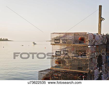 Stock Photography - Stacks of lobster traps by sea at sunrise. Fotosearch