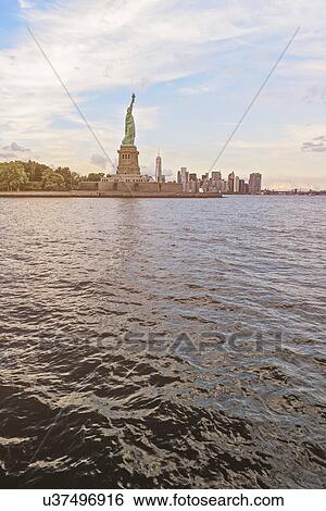 Stock Photograph - Statue of Liberty and financial district at dusk. Fotosearch