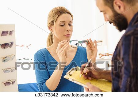 Stock Image - Woman and man choosing eyeglasses in store. Fotosearch