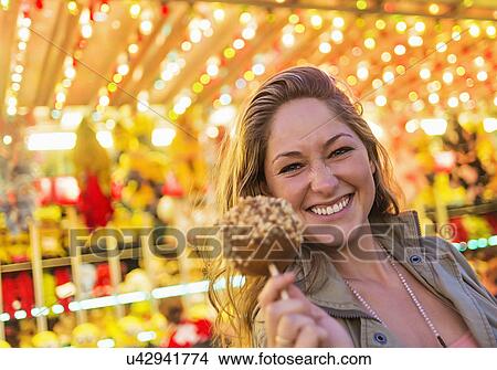 Woman holding caramel apple at funfair View Large Photo Image Picture - Woman holding caramel apple at funfair. Fotosearch