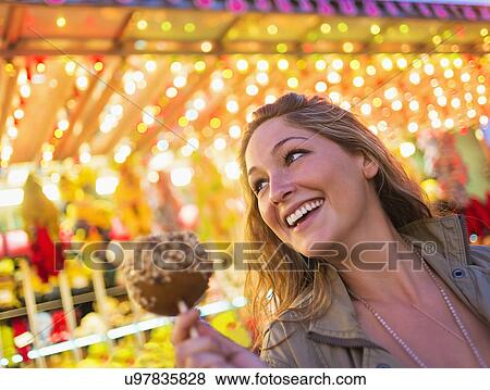 Stock Photo - Woman holding caramel apple at funfair. Fotosearch