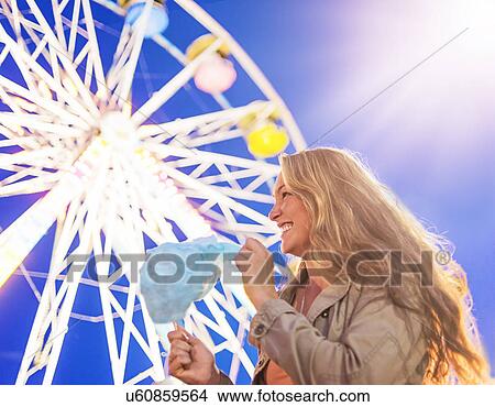 Picture - Woman holding cotton candy at funfair. Fotosearch