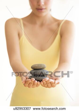 Stock Photo - Woman holding stack of pebbles. Fotosearch