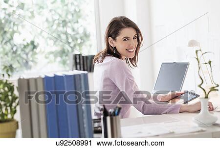 Young woman using digital tablet, looking at camera View Large Photo Image Stock Image - Young woman using digital tablet, looking at camera. Fotosearch