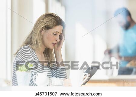 Young woman using tablet and man in background View Large Photo Image Stock Photo - Young woman using tablet and man in background. Fotosearch