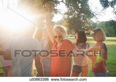 Adult friends dancing and drinking in park at sunset View Large Photo Image Stock Photo - Adult friends dancing and drinking in park at sunset. Fotosearch