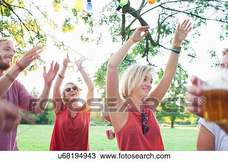 Stock Image - Adult friends dancing at sunset party in park. Fotosearch