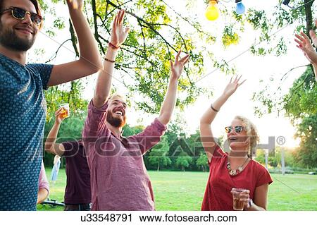 Adult friends dancing with arms raised at sunset party in park View Large Photo Image Stock Image - Adult friends dancing with arms raised at sunset party in park. Fotosearch