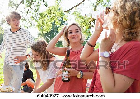 Stock Photo - Adult friends drinking wine at sunset park party. Fotosearch