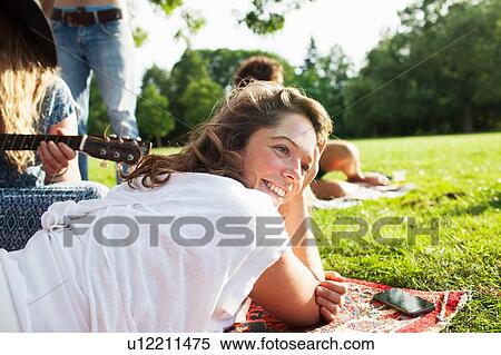 Adult friends playing acoustic guitar on rug at sunset park party View Large Photo Image Stock Photography - Adult friends playing acoustic guitar on rug at sunset park party. Fotosearch