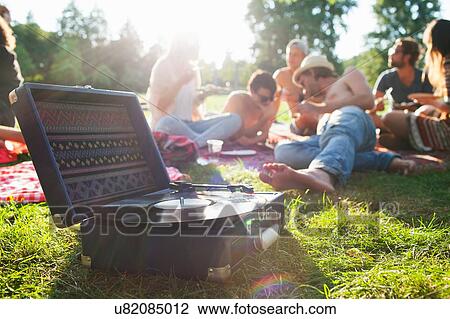 Adult friends relaxing and listening to record deck at sunset park party View Large Photo Image Stock Image - Adult friends relaxing and listening to record deck at sunset park party. Fotosearch
