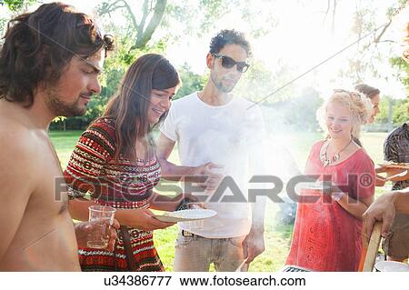Adult friends waiting for BBQ at sunset park party View Large Photo Image Stock Photo - Adult friends waiting for BBQ at sunset park party. Fotosearch