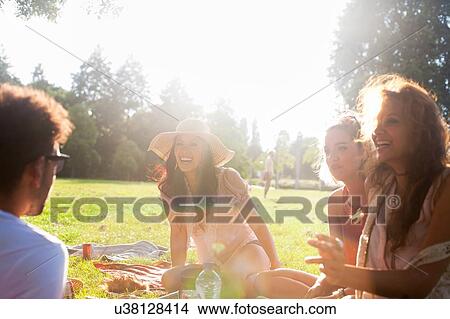 Adults friends chatting at sunset party in park View Large Photo Image Picture - Adults friends chatting at sunset party in park. Fotosearch