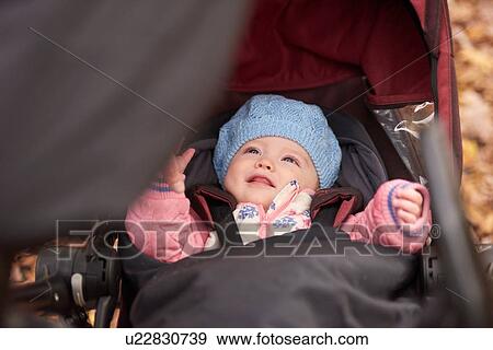 Baby girl wearing blue hat looking up from baby carriage View Large Photo Image Stock Photo - Baby girl wearing blue hat looking up from baby carriage. Fotosearch