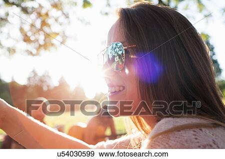 Close up of happy young woman at sunset park party View Large Photo Image Stock Photo - Close up of happy young woman at sunset park party. Fotosearch