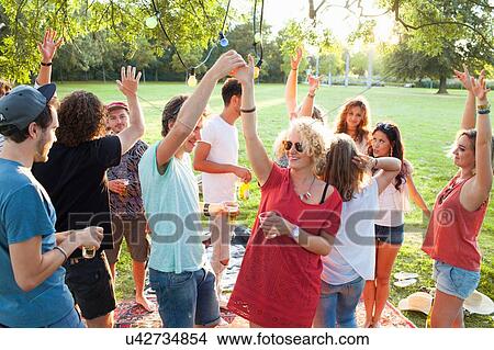 Crowd of adult friends dancing at party in park at sunset View Large Photo Image Picture - Crowd of adult friends dancing at party in park at sunset. Fotosearch