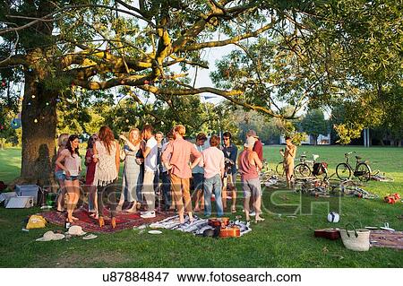 Crowd of adults under a tree at sunset party in park View Large Photo Image Stock Photo - Crowd of adults under a tree at sunset party in park. Fotosearch