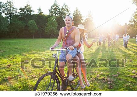 Crowd of partygoing adults arriving on cycles to sunset park party View Large Photo Image Stock Photograph - Crowd of partygoing adults arriving on cycles to sunset park party. Fotosearch