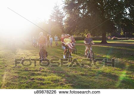 Crowds of adult friends arriving on bicycles to sunset park party View Large Photo Image Stock Photograph - Crowds of adult friends arriving on bicycles to sunset park party. Fotosearch
