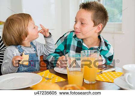 Cute female toddler licking fingers at kitchen table View Large Photo Image Stock Photography - Cute female toddler licking fingers at kitchen table. Fotosearch