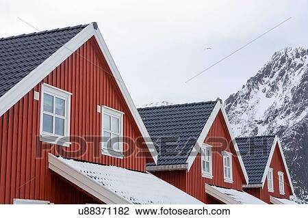 Stock Image - Detail of three houses and snow capped mountain, Svolvaer, Lofoten Islands, Norway. Fotosearch