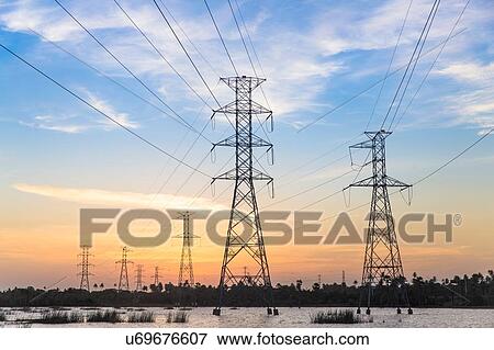 Stock Photo - Electricity pylons in waterlogged field at sunset, Taiba, Ceara, Brazil. Fotosearch