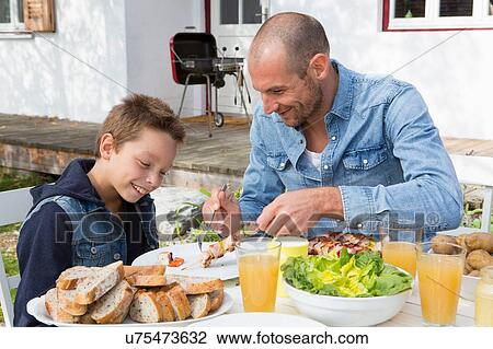 Father and son at garden barbecue table View Large Photo Image Stock Image - Father and son at garden barbecue table. Fotosearch