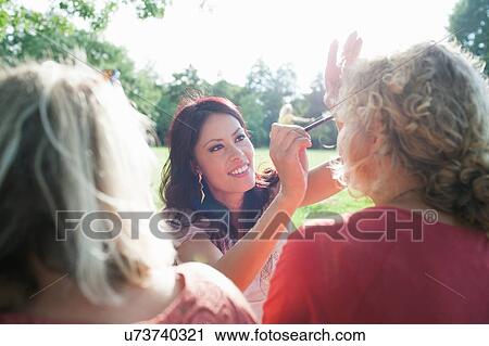 Female adult friends applying make up at sunset park party View Large Photo Image Stock Image - Female adult friends applying make up at sunset park party. Fotosearch