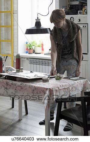 Stock Image - Female artist working at kitchen table. Fotosearch