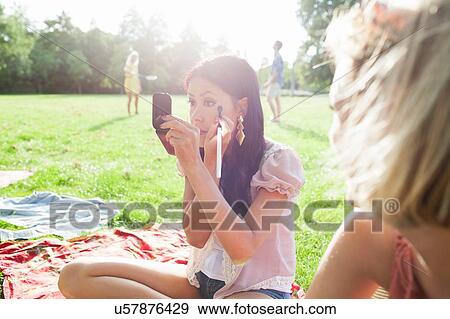 Female friends applying make up at park party View Large Photo Image Stock Photo - Female friends applying make up at park party. Fotosearch