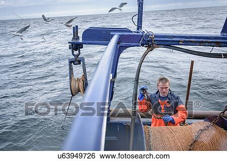 Stock Photograph - Fisherman preparing net on trawler. Fotosearch