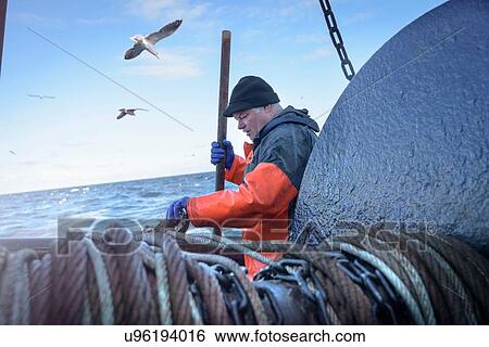 Stock Photograph - Fisherman preparing net on trawler. Fotosearch