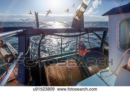 Stock Photo - Fisherman preparing nets on trawler. Fotosearch