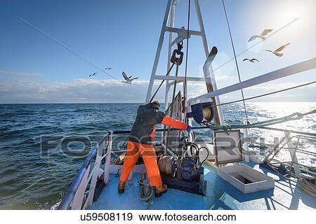 Stock Photo - Fisherman standing on deck of trawler. Fotosearch