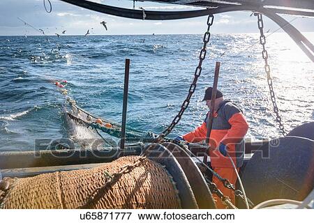 Stock Photo - Fisherman tending nets on trawler. Fotosearch