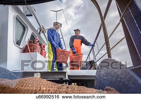 Stock Photograph - Fishermen with catch of fish on deck of trawler. Fotosearch