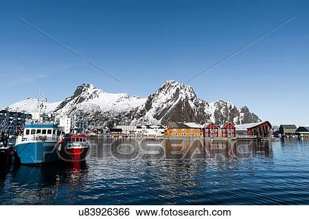 Stock Photograph - Fishing boats in harbour and snow capped mountains, Svolvaer, Lofoten Islands, Norway. Fotosearch