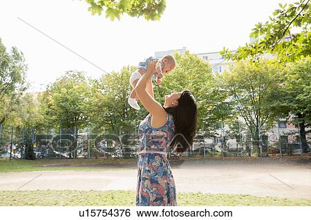 Grandmother holding up baby granddaughter in park View Large Photo Image Stock Photograph - Grandmother holding up baby granddaughter in park. Fotosearch