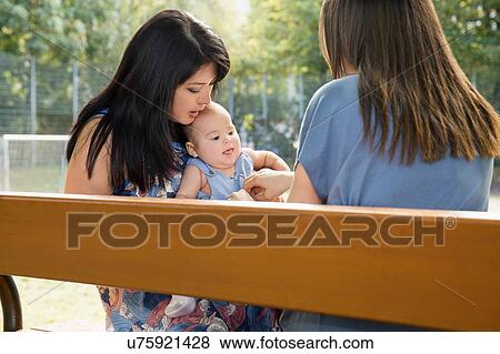 Grandmother sitting on park bench with baby granddaughter and daughter View Large Photo Image Stock Photo - Grandmother sitting on park bench with baby granddaughter and daughter. Fotosearch