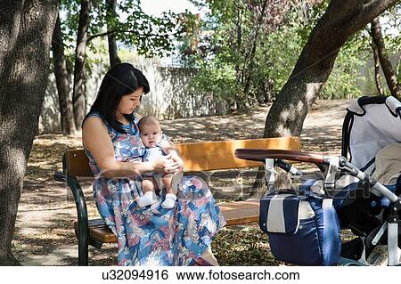 Stock Photograph - Grandmother sitting on park bench with baby granddaughter. Fotosearch