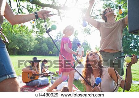 Group of friends hanging decorative lights at sunset park party View Large Photo Image Stock Photo - Group of friends hanging decorative lights at sunset park party. Fotosearch