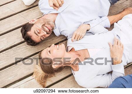 Group of friends lying in a row, on pier, elevated view View Large Photo Image Picture - Group of friends lying in a row, on pier, elevated view. Fotosearch