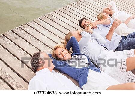 Group of friends lying in a row, on pier, elevated view View Large Photo Image Stock Image - Group of friends lying in a row, on pier, elevated view. Fotosearch