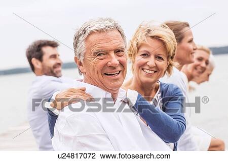 Stock Image - Group of friends, sitting outdoors, smiling. Fotosearch