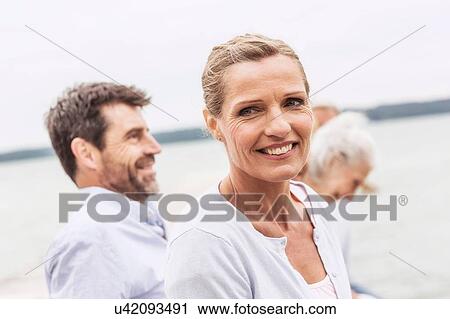 Group of friends sitting outdoors, smiling View Large Photo Image Stock Image - Group of friends sitting outdoors, smiling. Fotosearch
