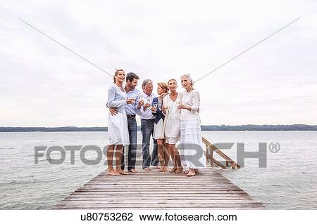 Group of friends standing on pier, holding wine glasses View Large Photo Image Stock Image - Group of friends standing on pier, holding wine glasses. Fotosearch